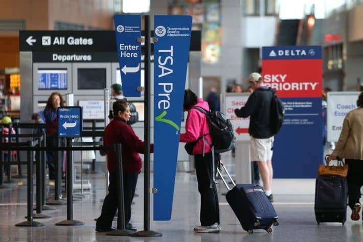 An airport agent checks a passenger's ID at a TSA PreCheck checkpoint.