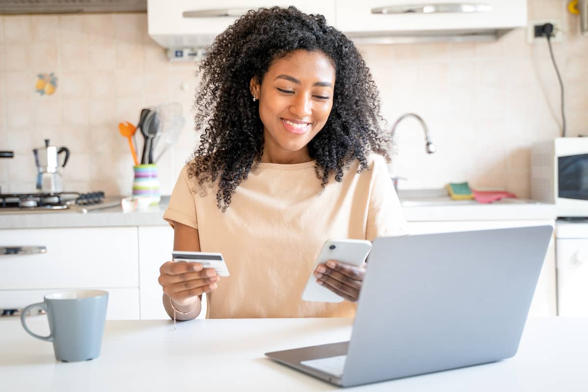 Woman shopping online with a credit card in her kitchen