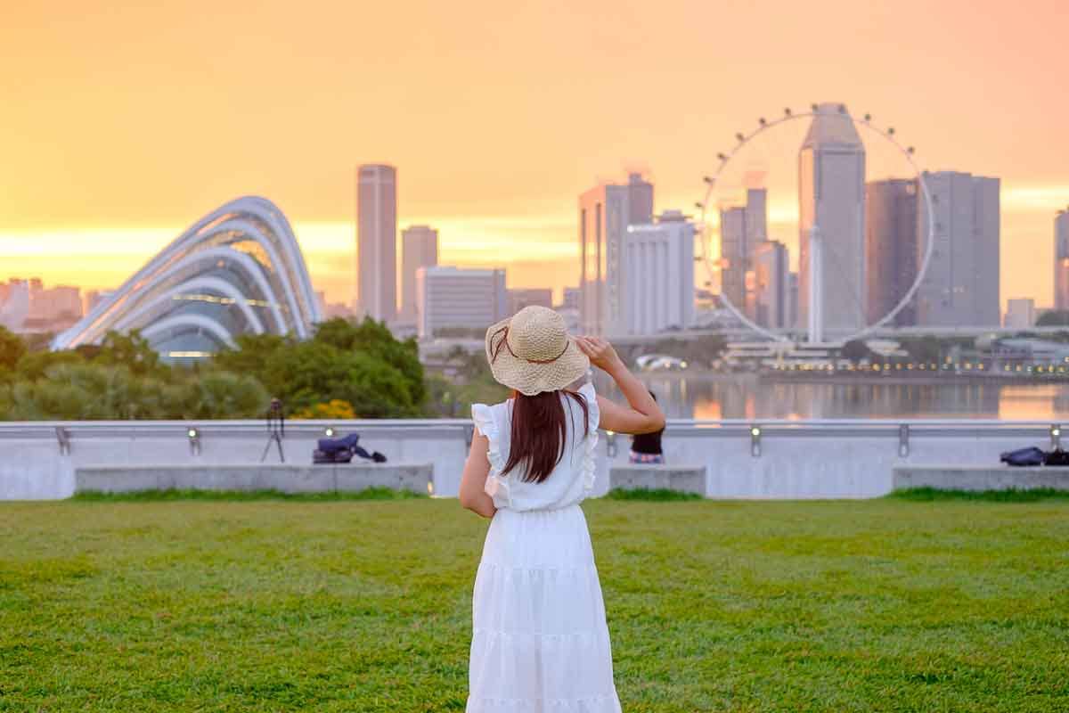 A young woman traveler at sunset stands in front of downtown Singapore