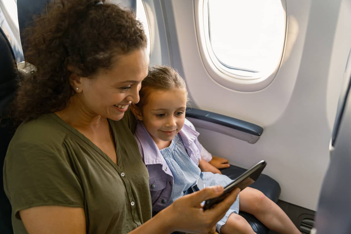 Mother and young daughter watch a tablet together on a plane