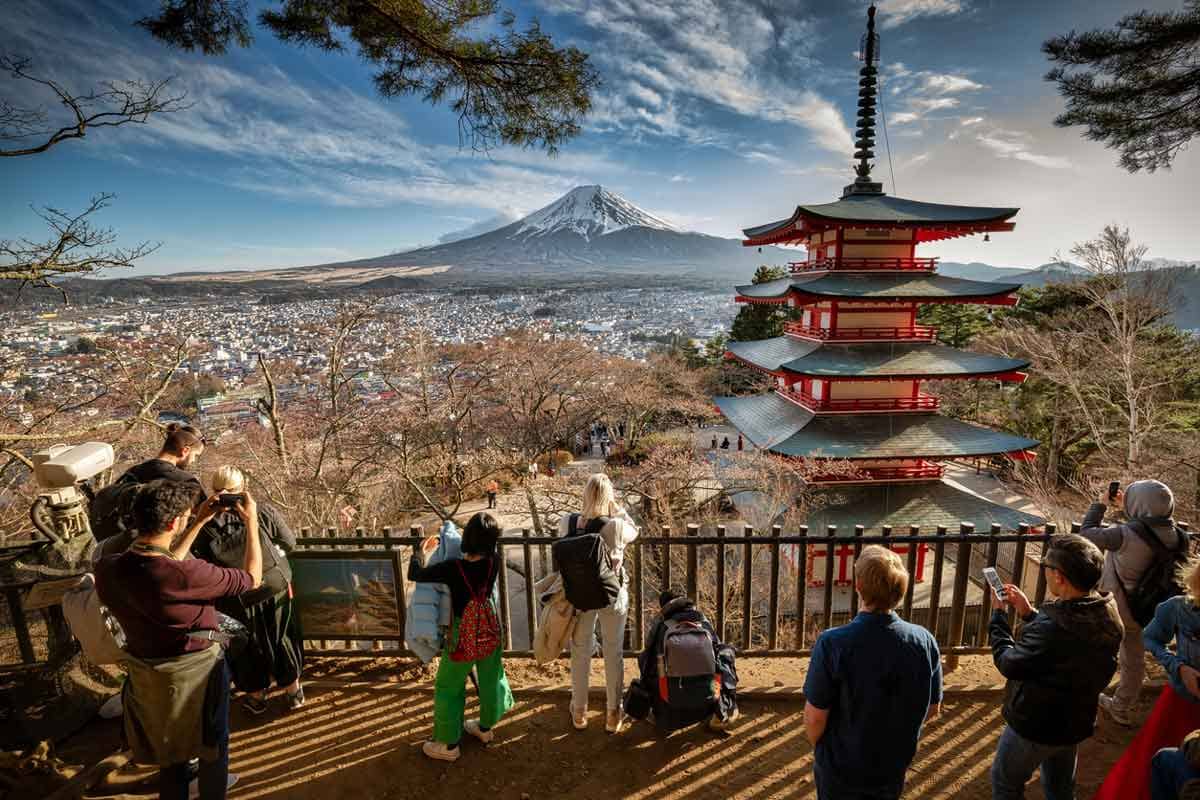 Tourists taking photos of the Chureito Pagoda in Japan with Mount Fuji in the background.