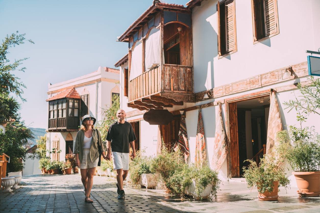 A couple walks together holding hands while on vacation.