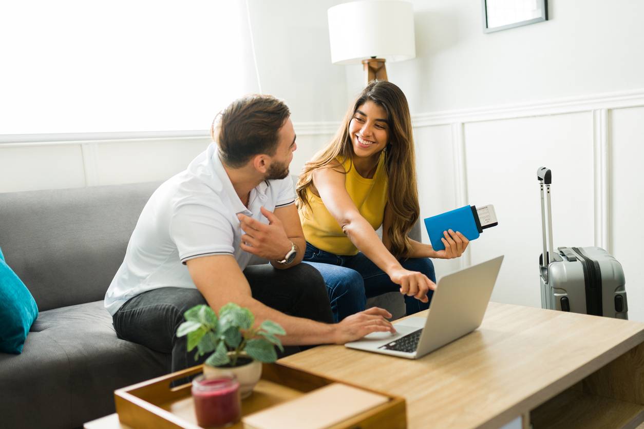 Smiling couple booking travel together on a laptop at home