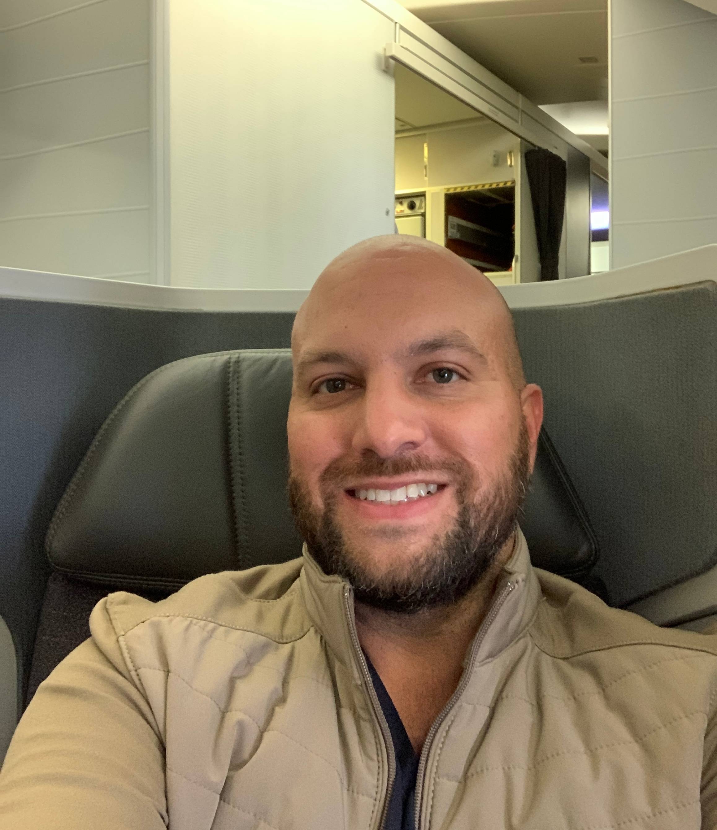 Headshot of the author Juan Ruiz sitting in a premium-cabin seat on a plane.