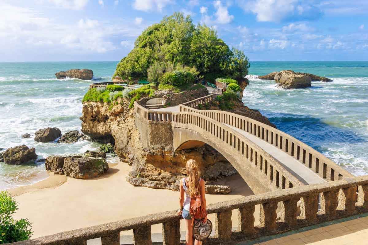 A woman tourist stands in front of the famous bridge to the island in Biarritz, a basque country in France.