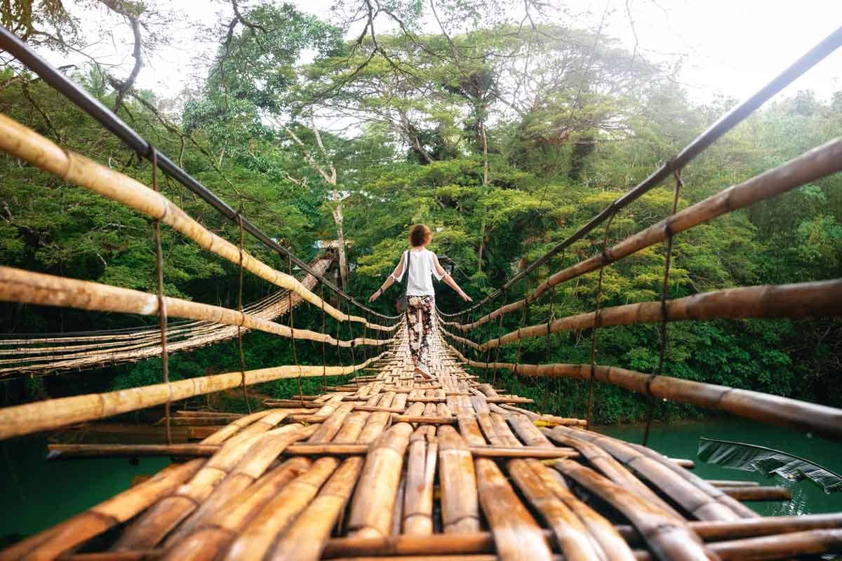 A woman tourist on a bamboo suspension bridge across the Loboc River in Bohol, Philippines.