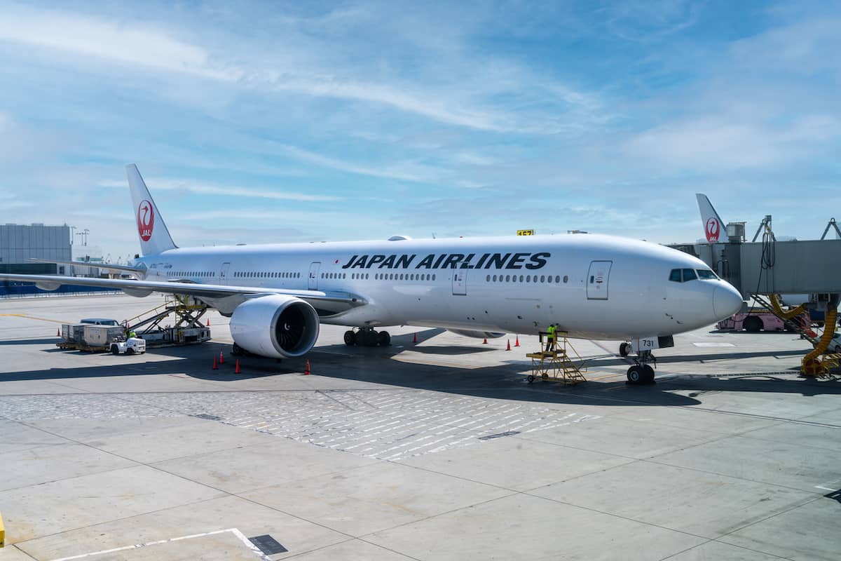 A Japan Airlines (JAL) plane sitting on the ground at a gate.
