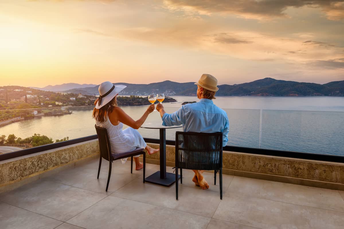 Couple toasting on a hotel balcony above the water at sunset
