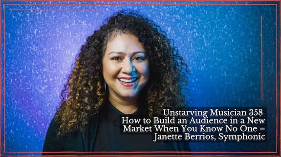 Janette Berrios smiling, with long curly hair, wearing a black collared top against a blue and purple backdrop.