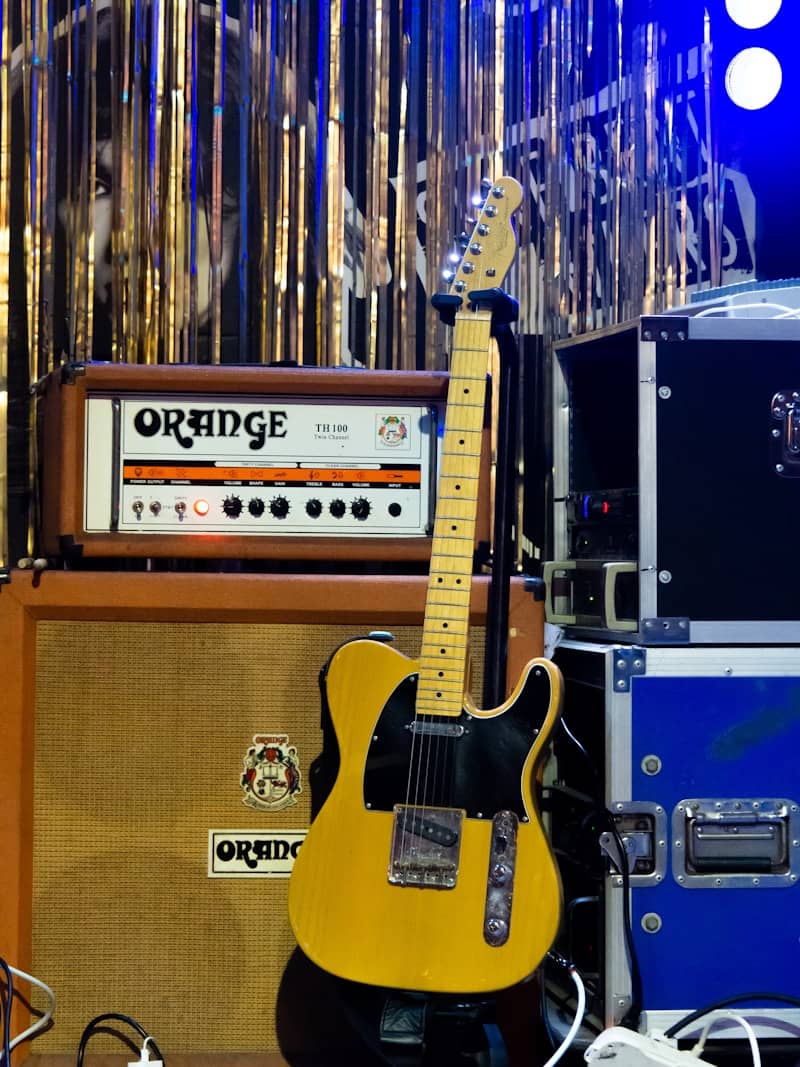 Guitar with orange amplifier on stage.