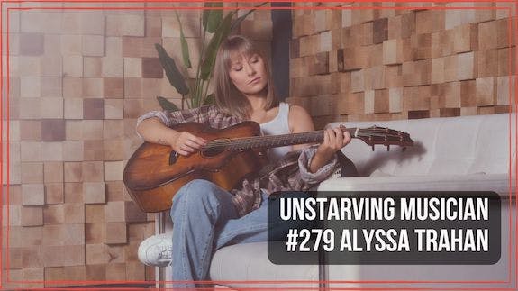 Alyssa Trahan sitting on a sofa playing acoustic guitar