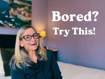 smiling woman sitting on a cream colored comforter