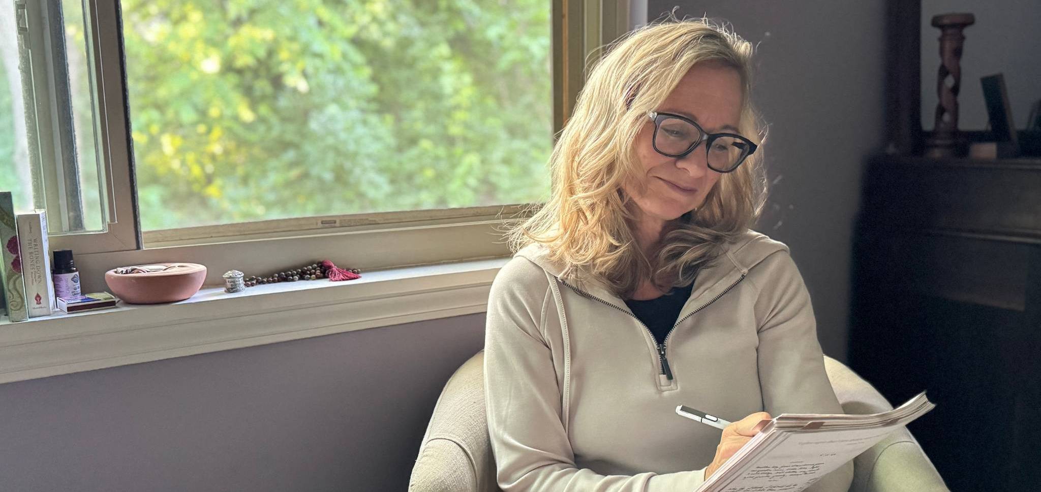 woman sitting by window journaling