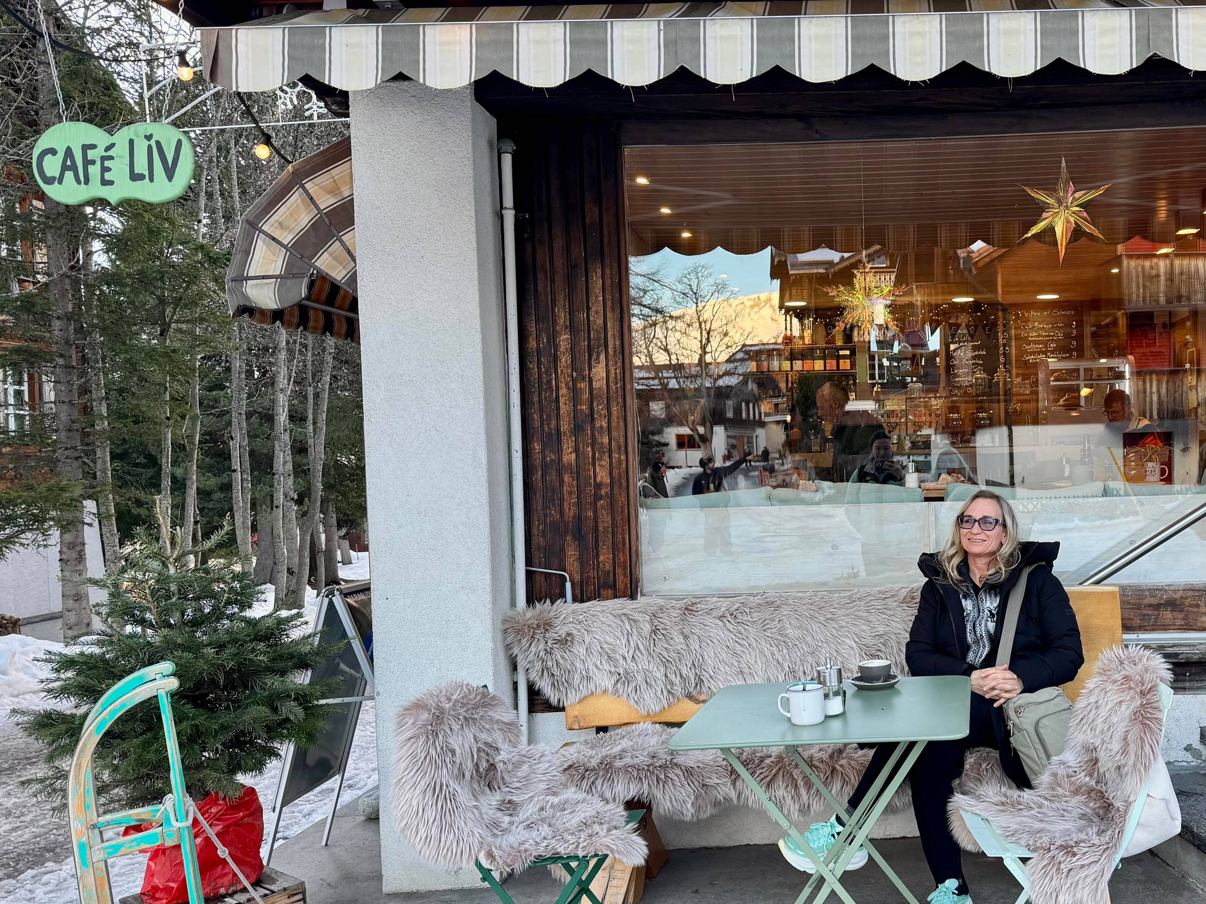 woman sitting outside at a Swiss cafe on a chilly day