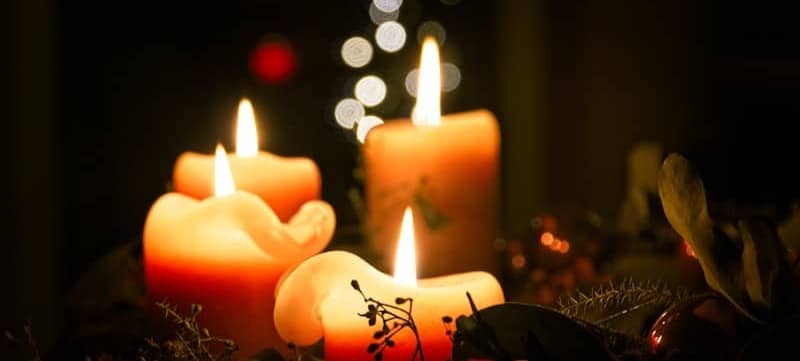 Four lit candles with bokeh lights in background