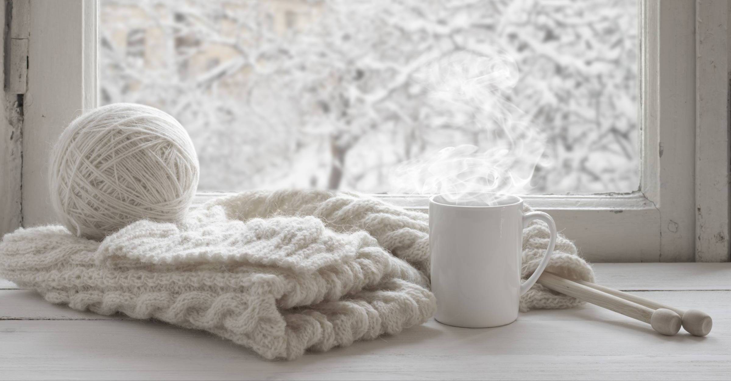 white ball of yarn, white knitting, white mug, snowy background