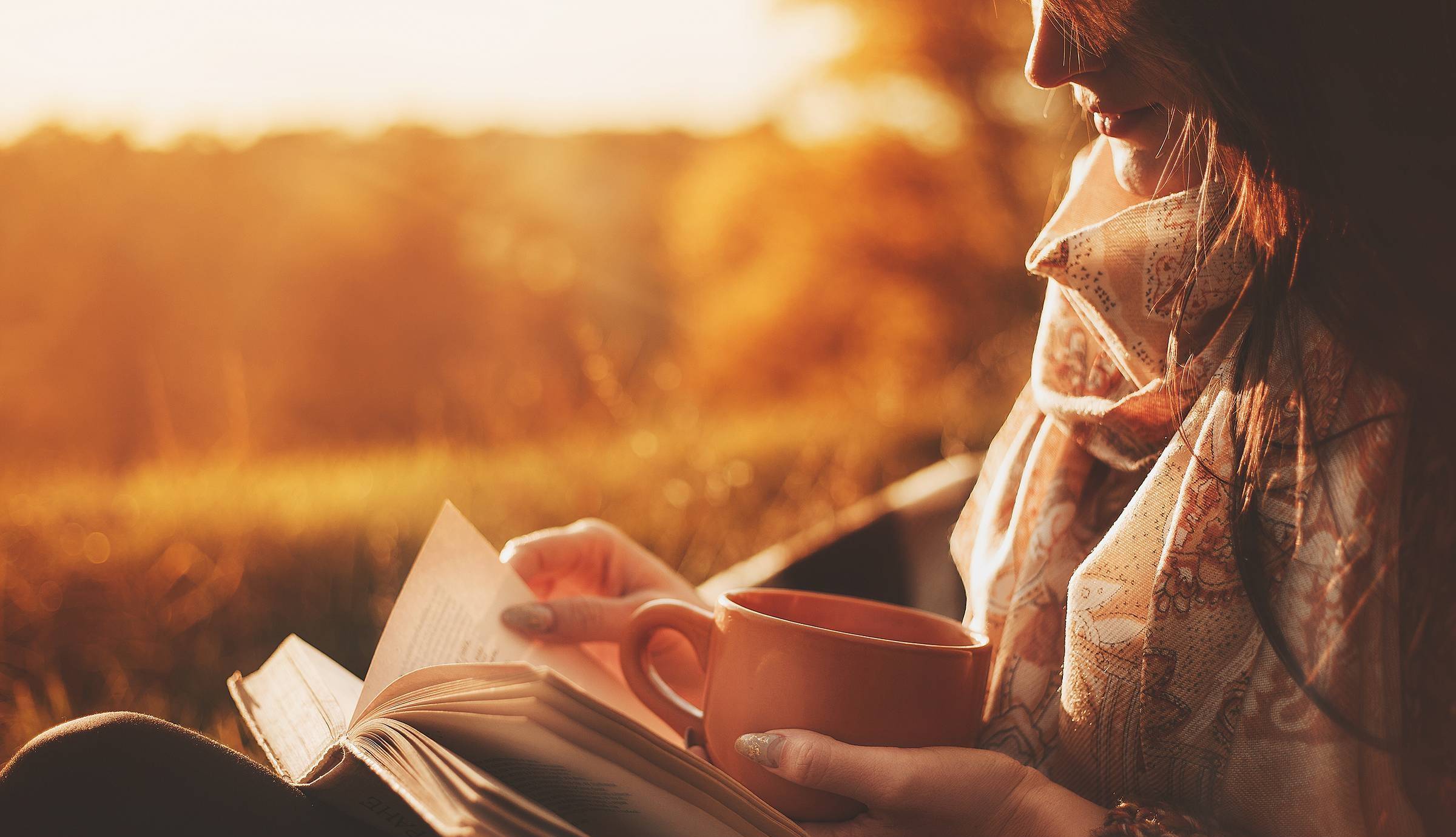 woman reading in morning sunlight with mug