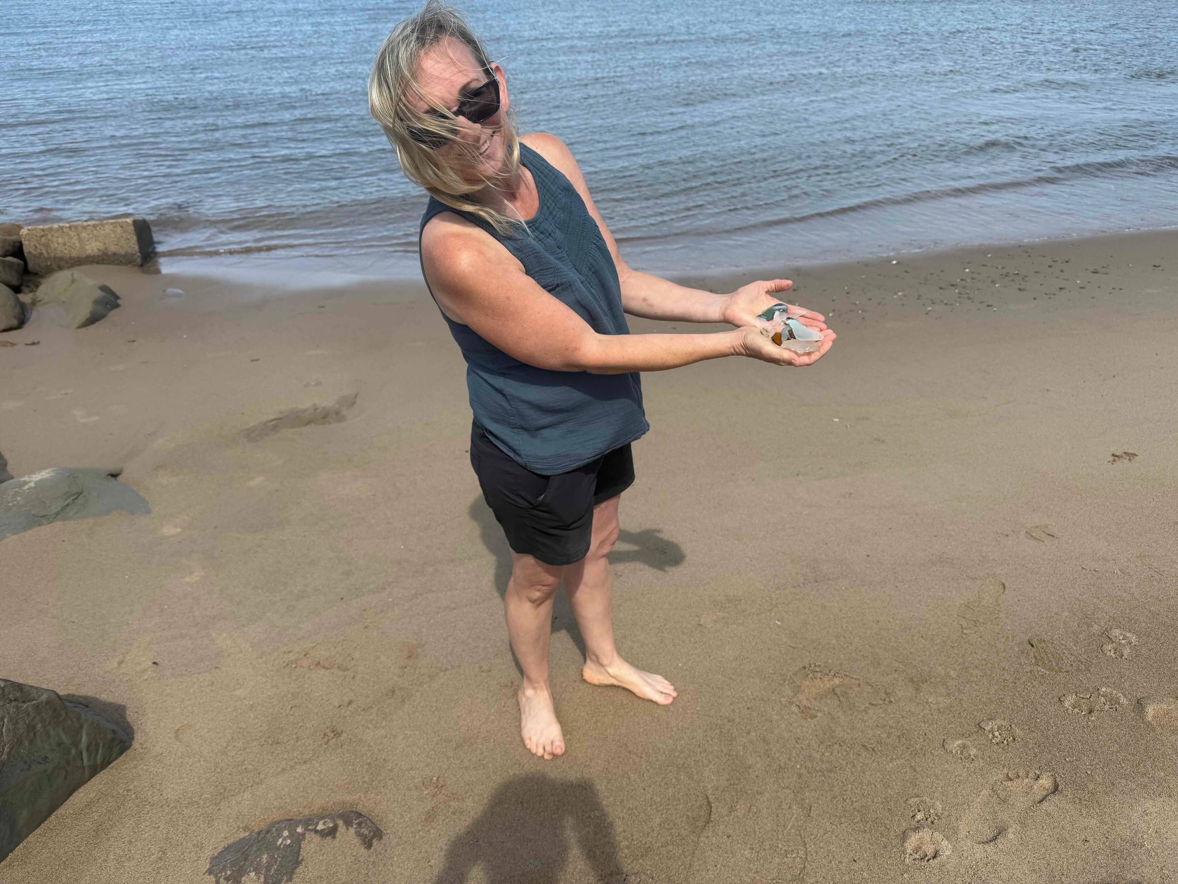woman with sea glass in cupped hands standing on a beach