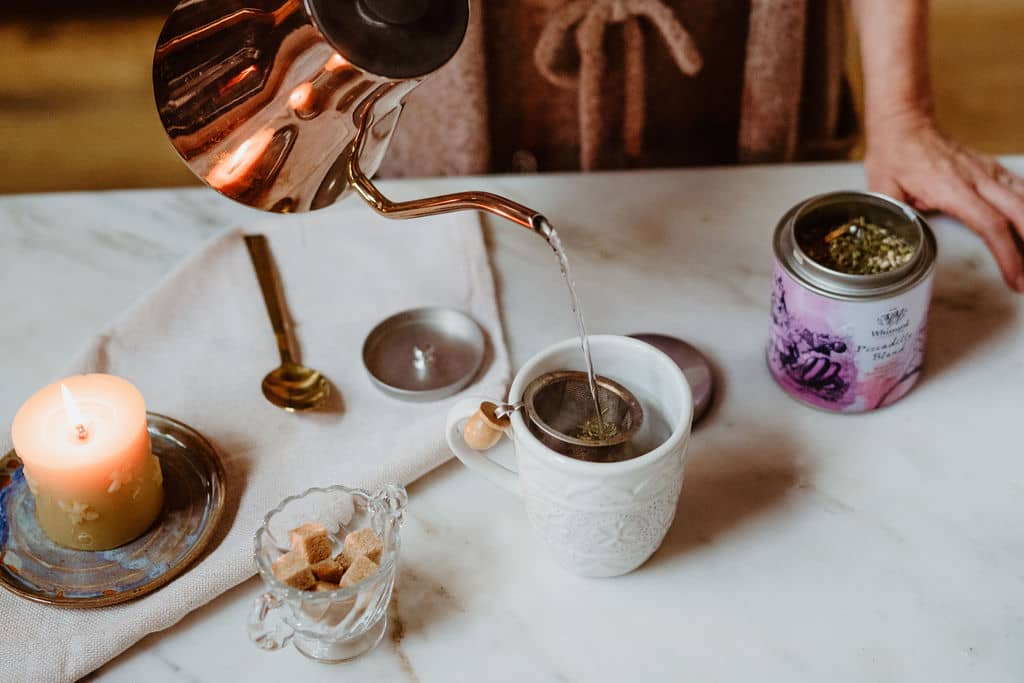 pouring water from a copper kettle to make tea