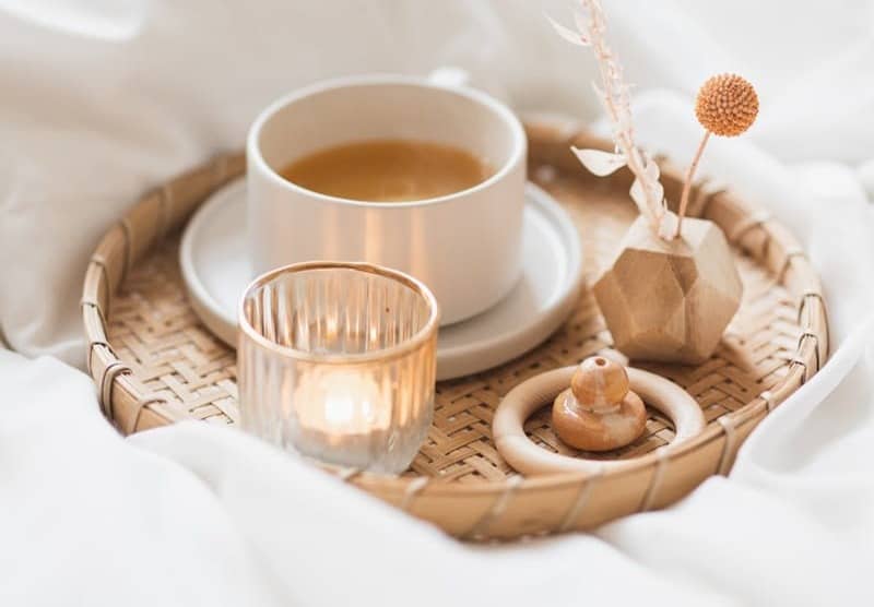 cup of tea and candle on a woven platter