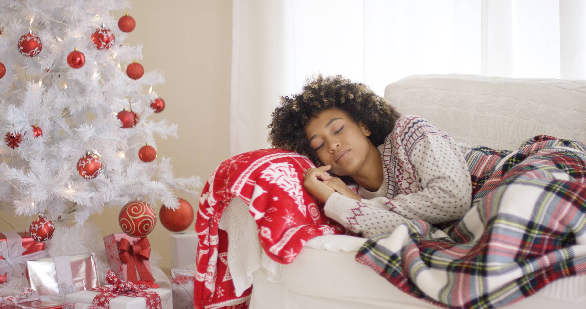 woman sleeping on couch by Christmas tree