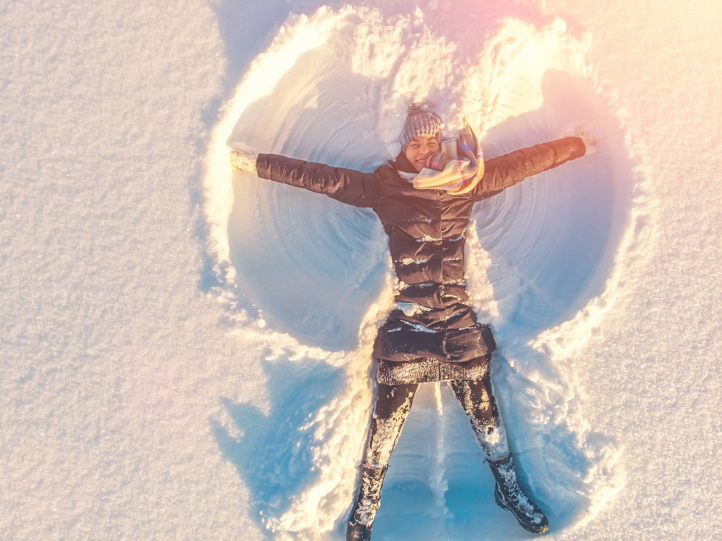 woman in black snowsuit making snow angels