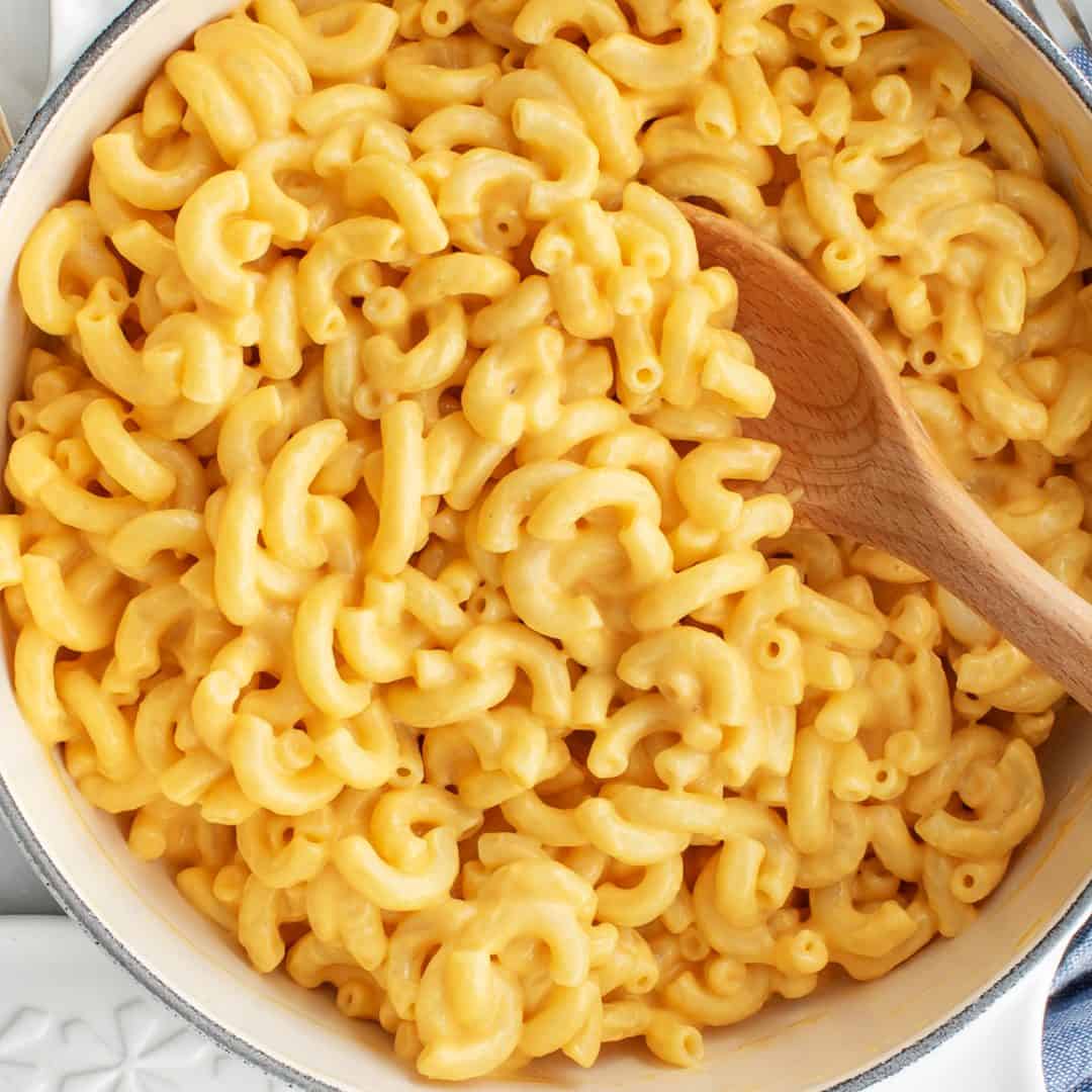 Vegan mac and cheese in pot with wooden spoon