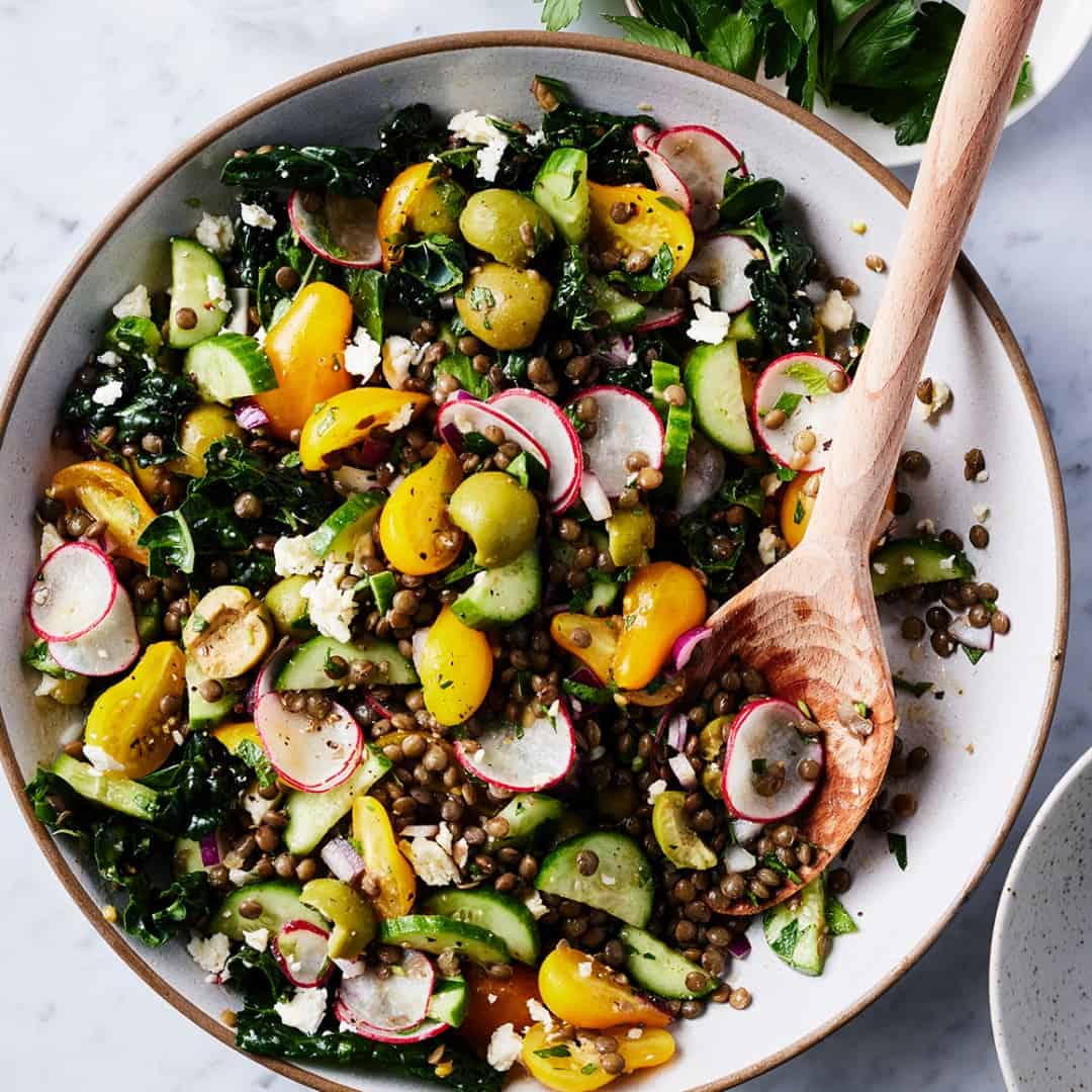 Lentil salad in serving bowl with wooden spoon