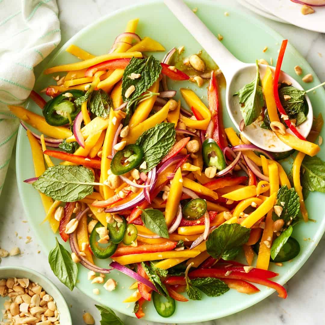 Mango salad on a plate with serving spoon