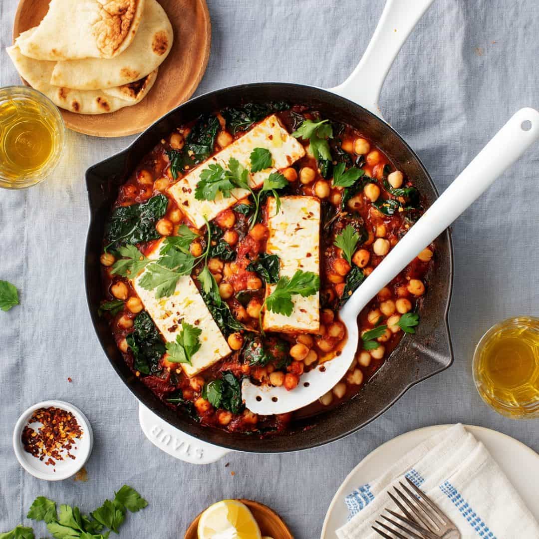 Baked feta in skillet with chickpeas, kale, and tomato sauce