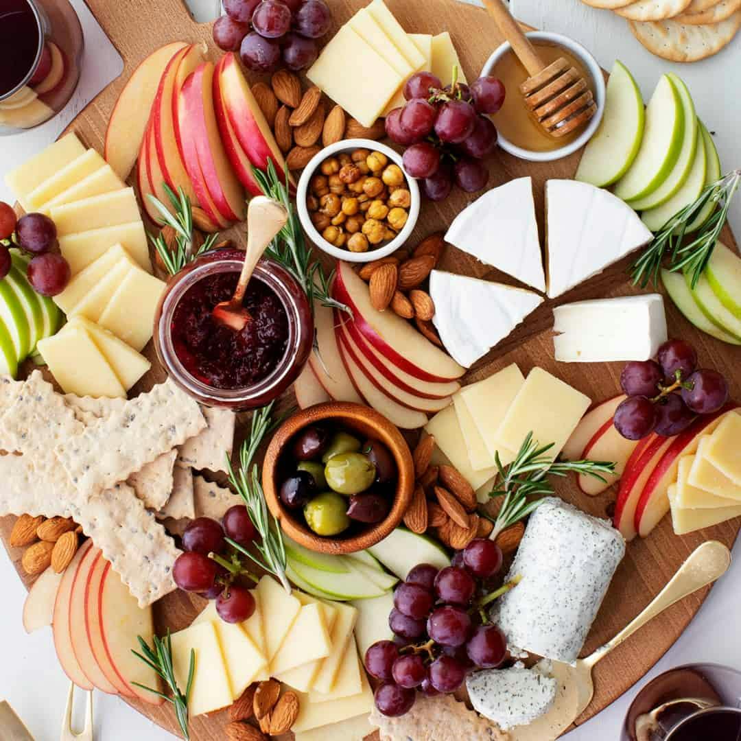 Cheese board with apples, olives, and grapes