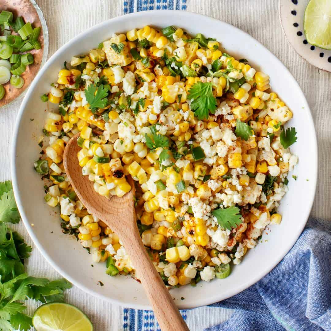 Mexican street corn salad in bowl with wooden serving spoon