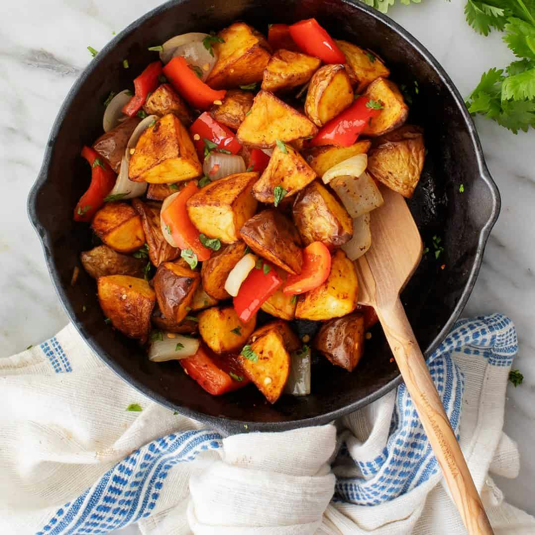 Breakfast potatoes in a skillet with peppers and onions