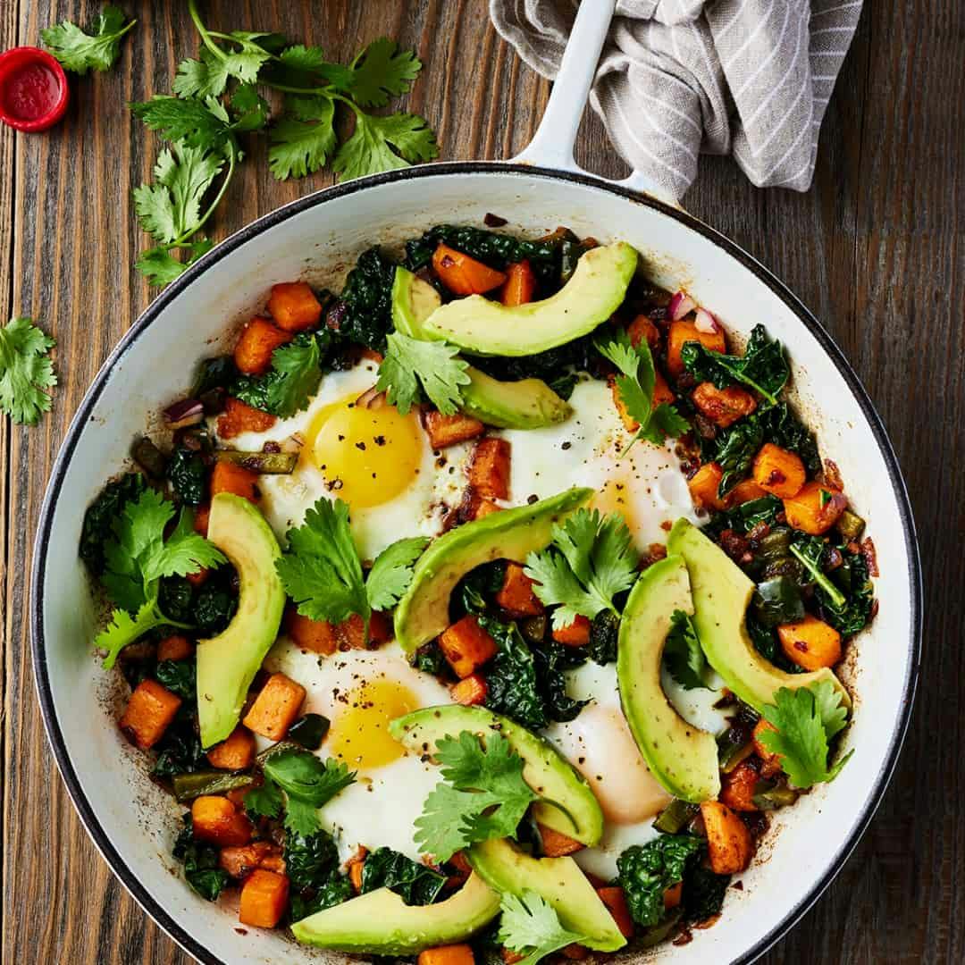 Sweet potato hash in skillet with avocado and cilantro