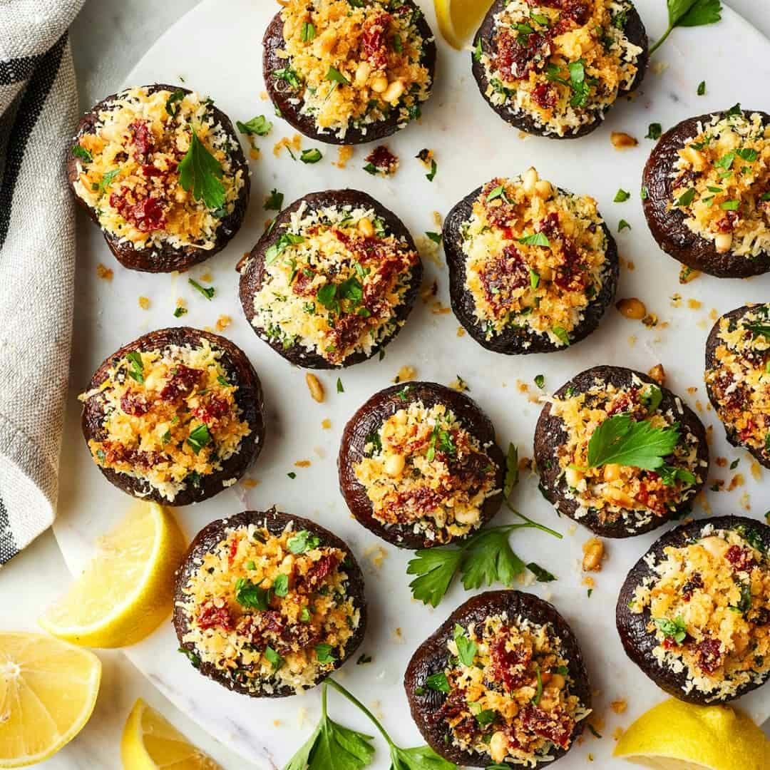 Stuffed mushrooms on a serving board with lemon wedges