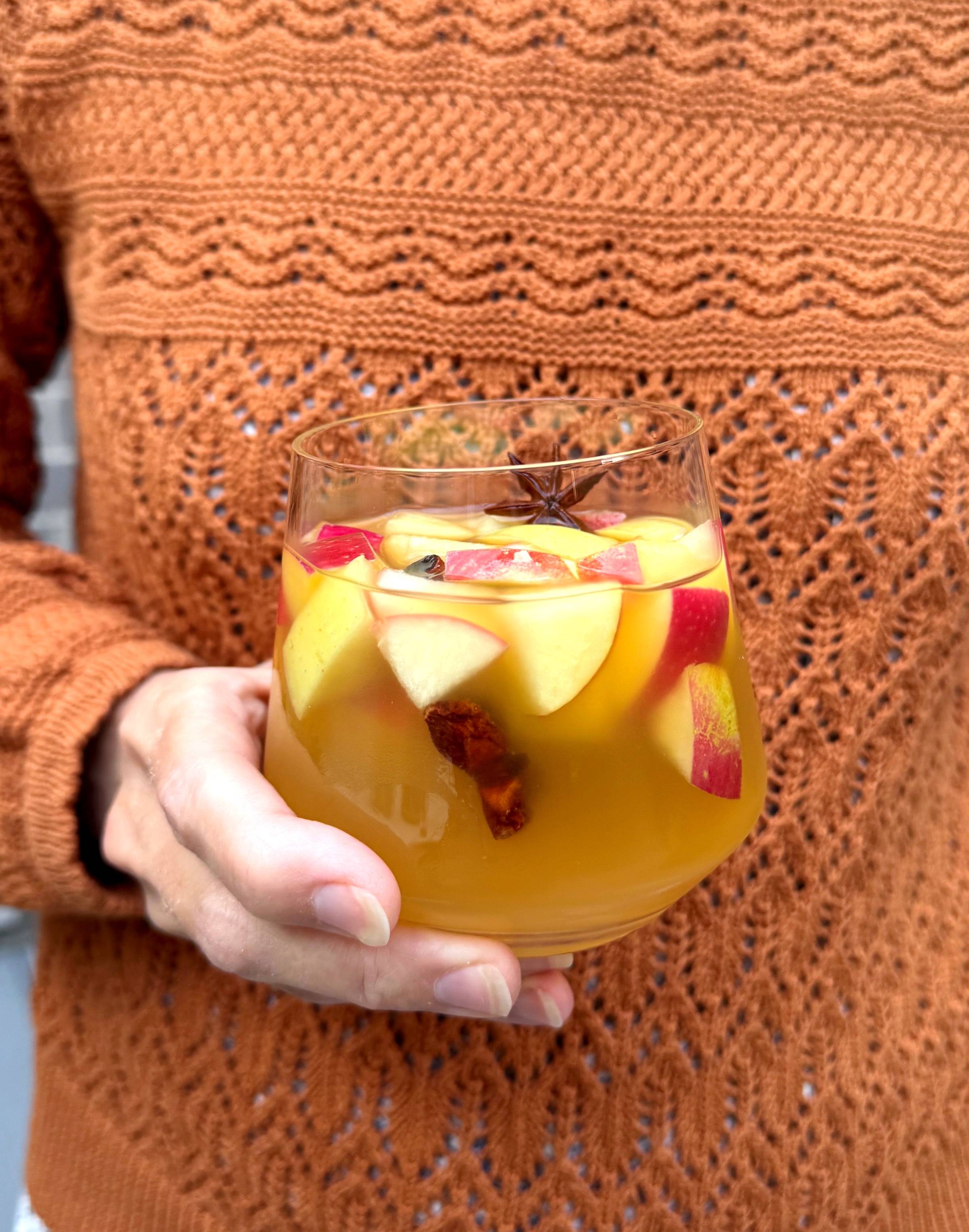 Hand holding glass of apple cider sangria