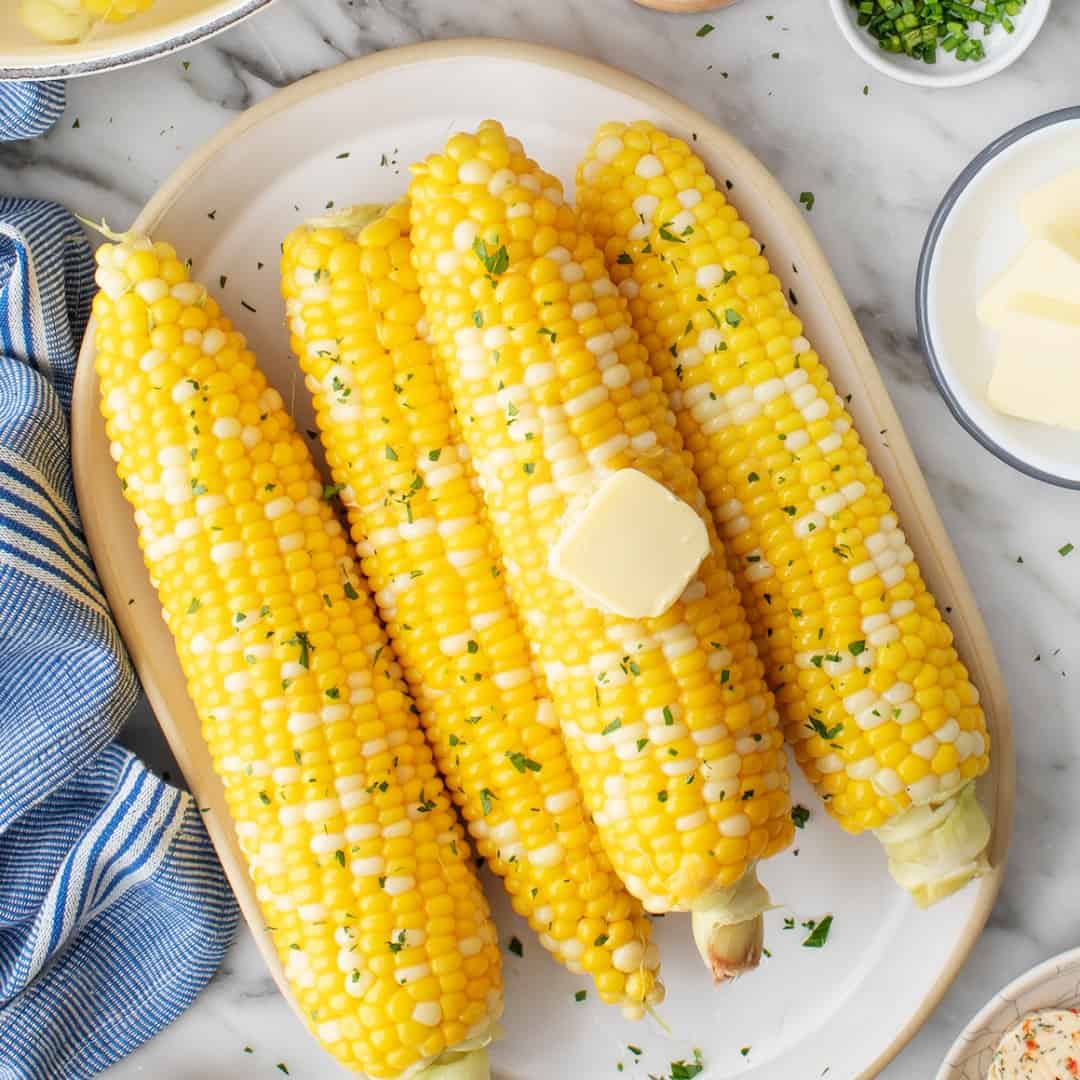 Plate of corn on the cob with butter and herbs