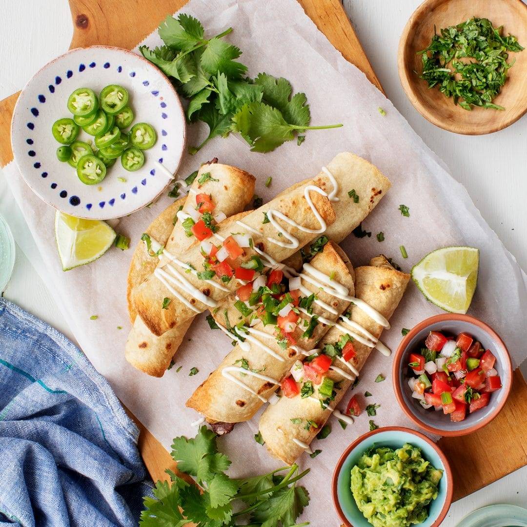 Homemade taquitos with salsa, cilantro, and guacamole