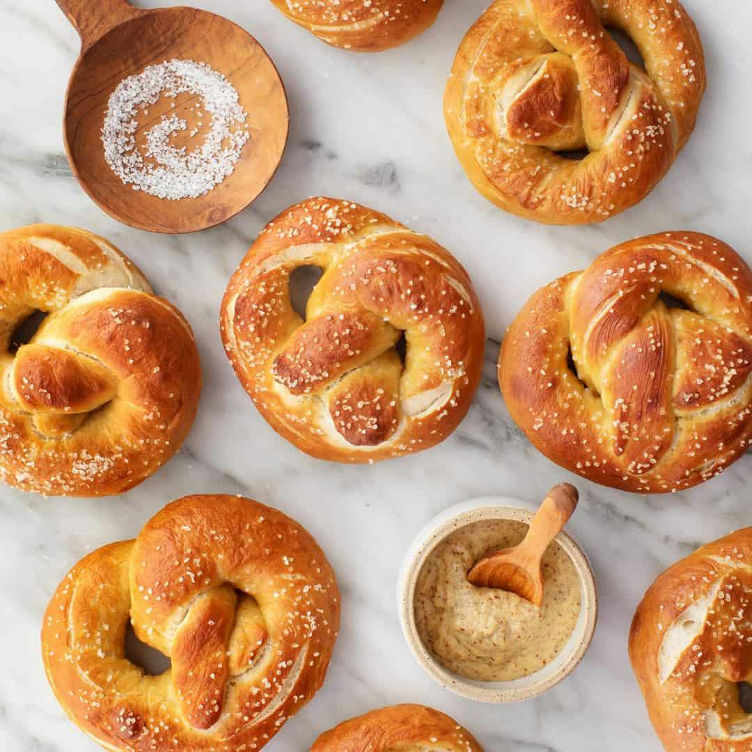 Soft pretzels and bowl of grainy mustard on marble