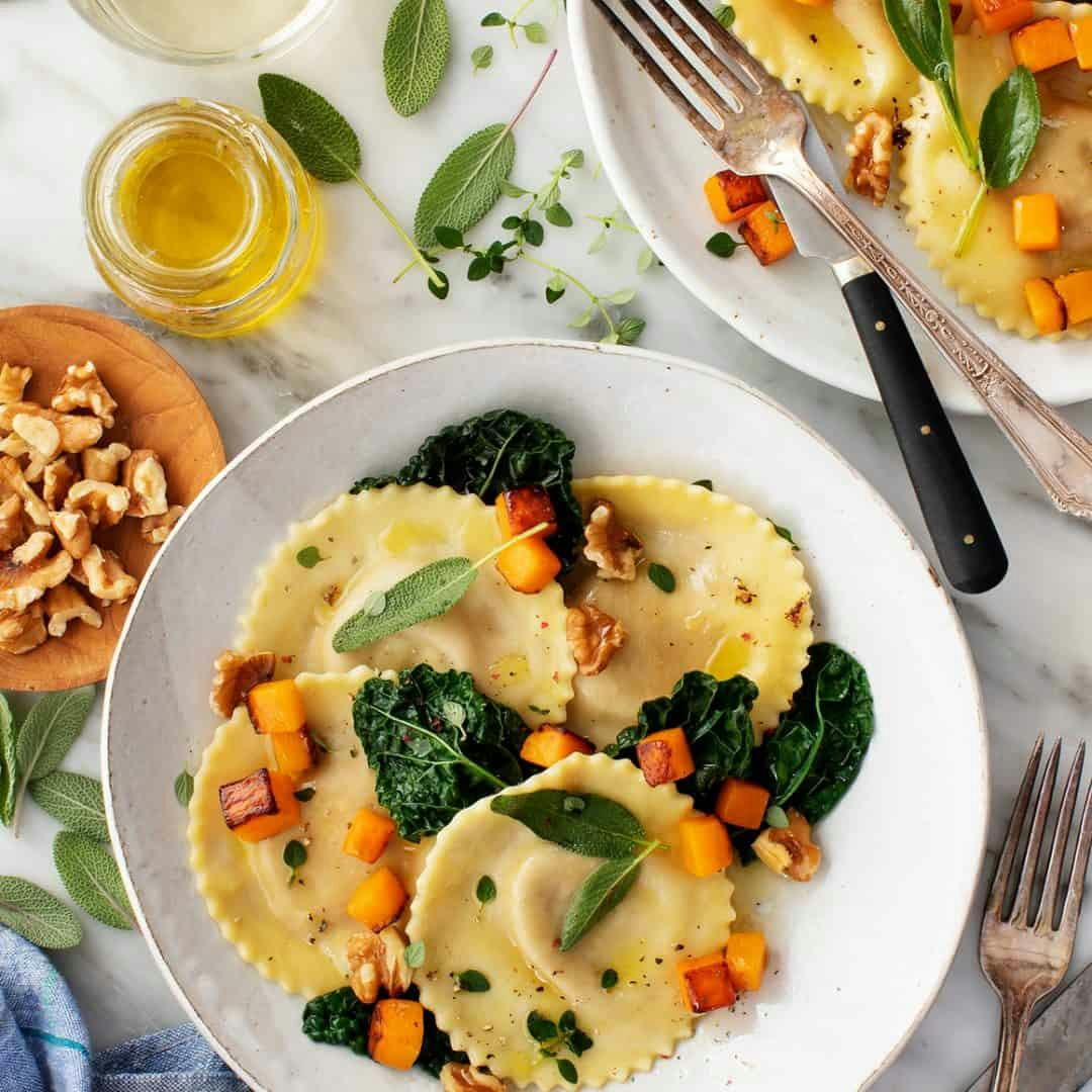 Butternut squash ravioli on a plate with kale and roasted butternut squash