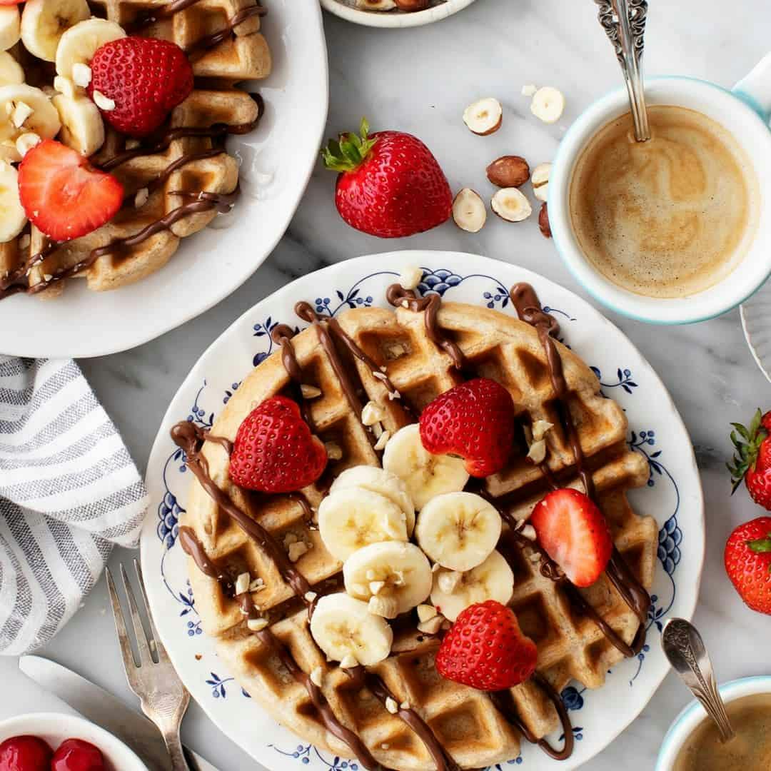 Homemade waffles topped with bananas, strawberries, and nutella