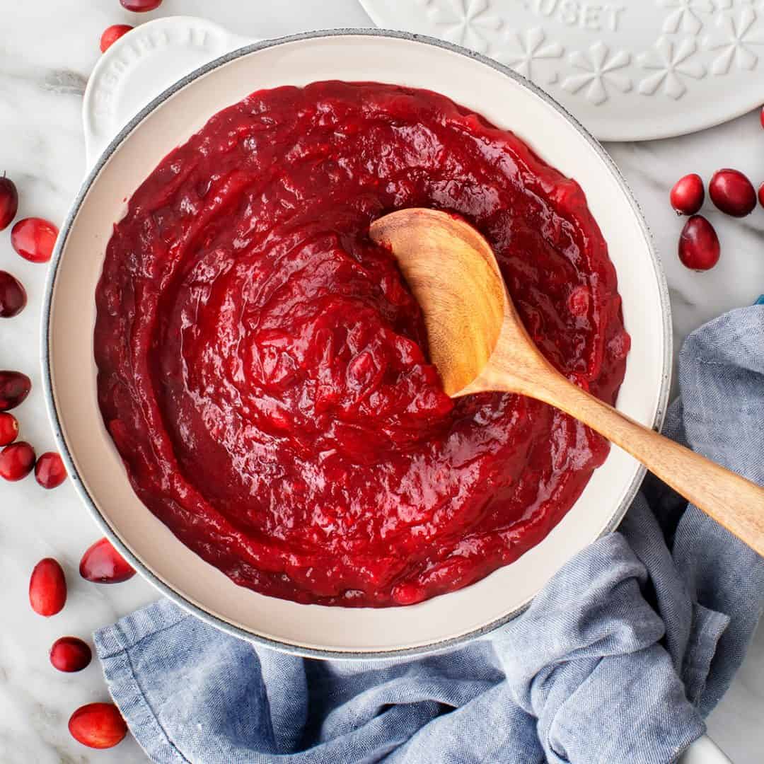 Cranberry sauce in saucepan with wooden spoon