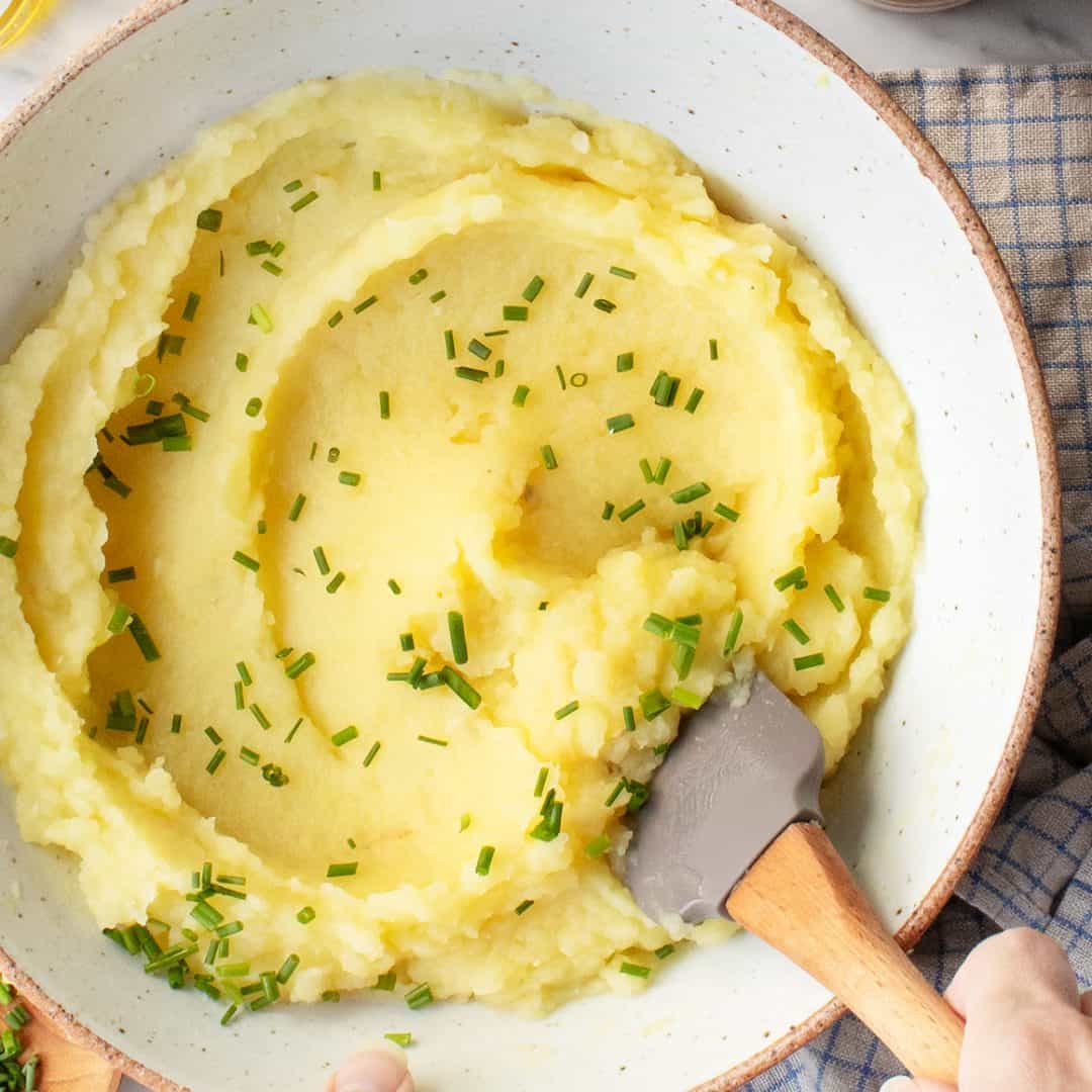 Roasted garlic mashed potatoes in serving bowl with spatula