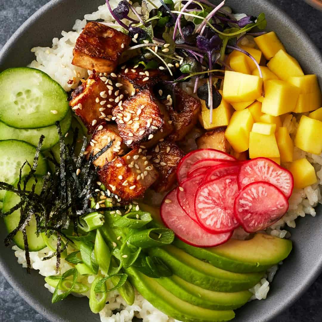 Sushi bowl with tofu, pickled radishes, avocado, mango, nori, and cucumber