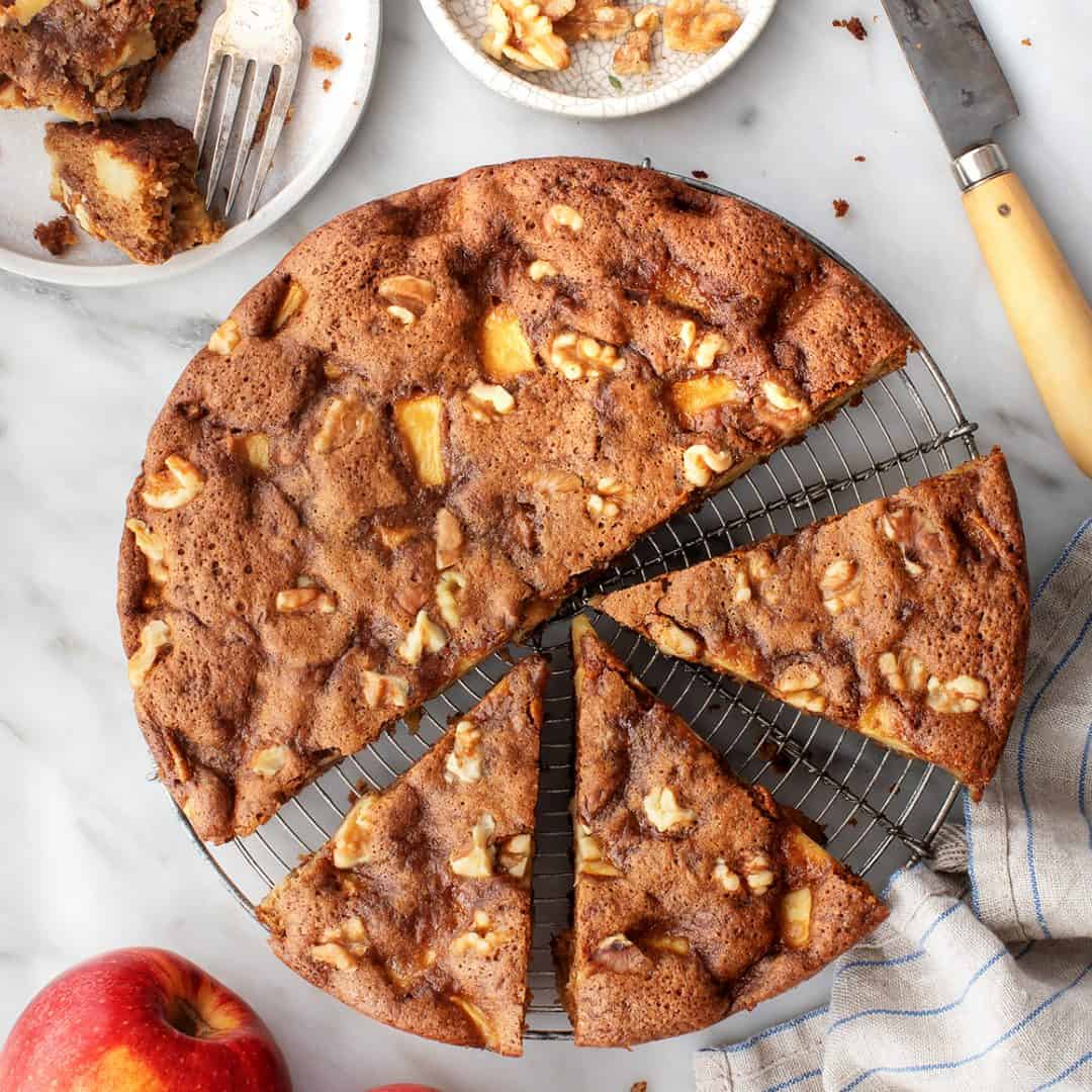 Apple cake on cooling rack with slice cut out