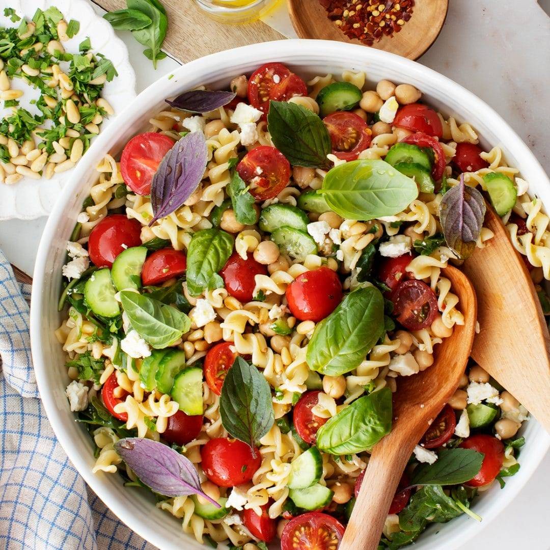 Bowl of pasta salad with tomatoes, basil, and feta cheese