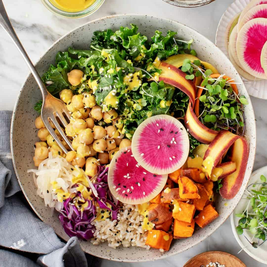 Buddha bowl with fresh veggies, chickpeas, brown rice, and turmeric tahini sauce