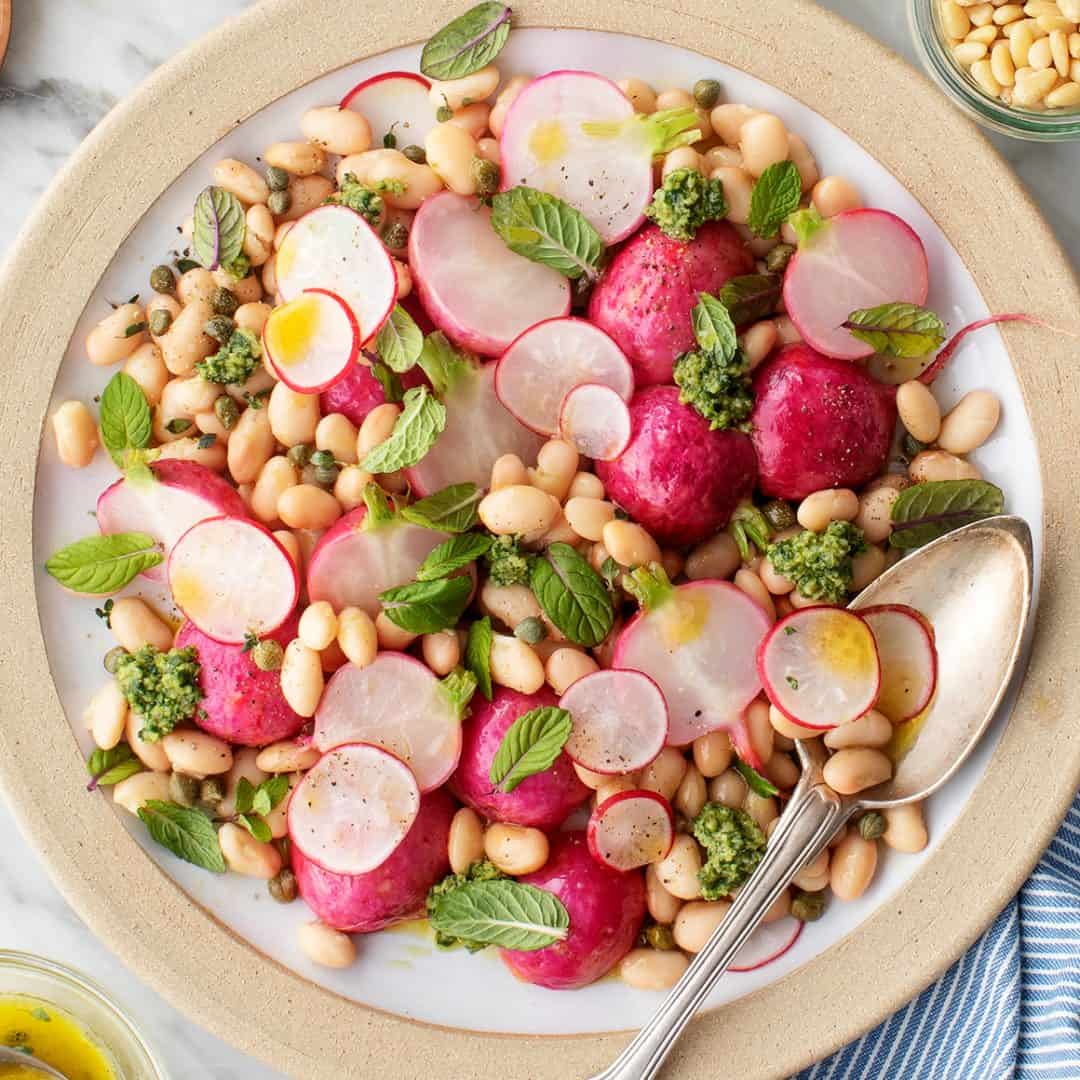 Radish and white bean salad on a plate with serving spoon