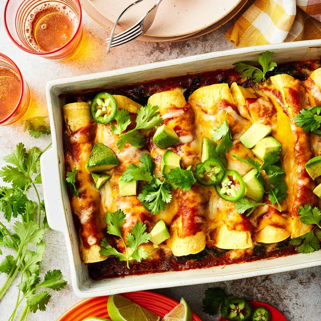 Easy cheese enchiladas topped with avocado, cilantro, and jalapenos in baking dish