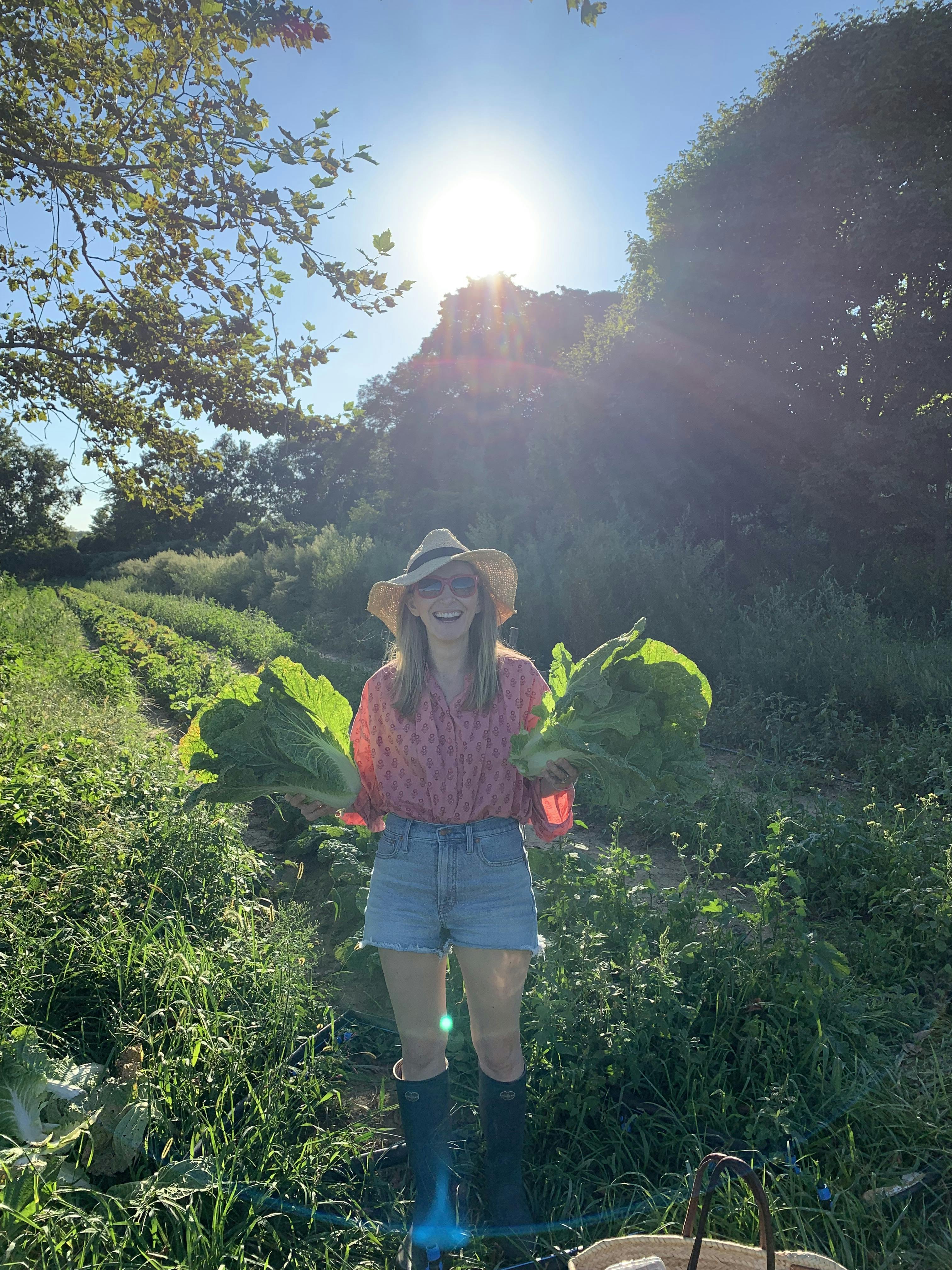 A photo of Ingrid holding two cabbages in a farm field